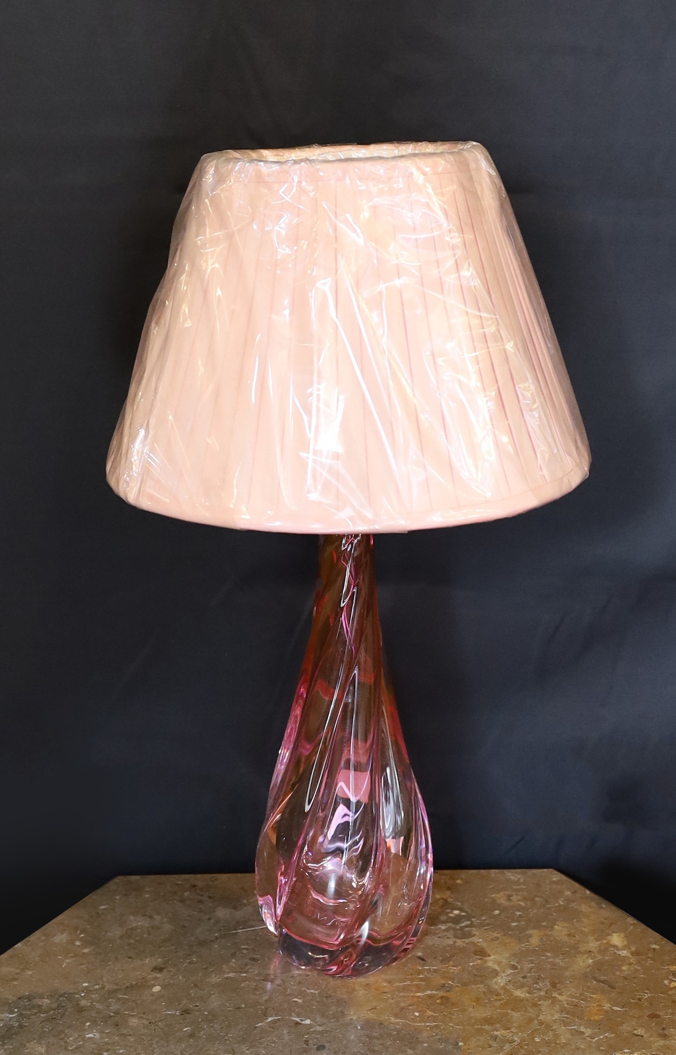 A 1960s Val Saint Lambert cranberry tinted glass table lamp, of twisted form, with replacement pleated silk shade, height 36cm